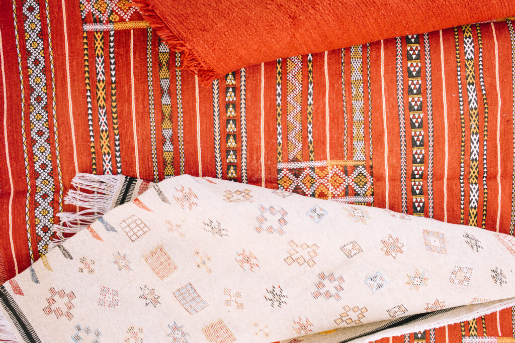 Handicrafts for Home A colorful handmade rug with geometric patterns on a wooden floor.