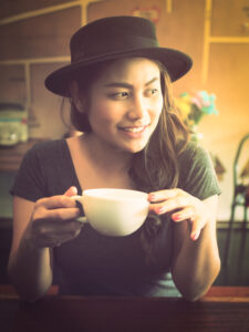 A steaming cup of chai next to a window, with spices like ginger, cardamom, and cloves scattered around.