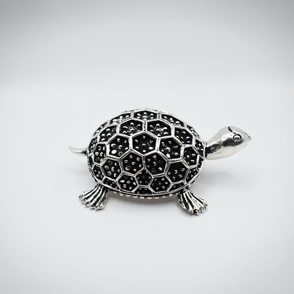 A beautiful silver puja thali shaped like a turtle, with intricate details on the shell.