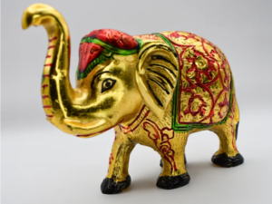 Close-up of a golden elephant figurine with intricate red and green decorations